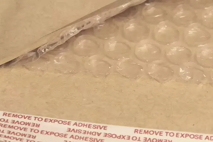 Close-up of the bubble lining inside a kraft mailer, above the adhesive release strip