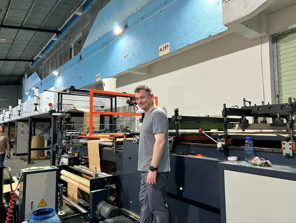 Noel, co-owner, beside a paper bag making machine at our Dongguan factory